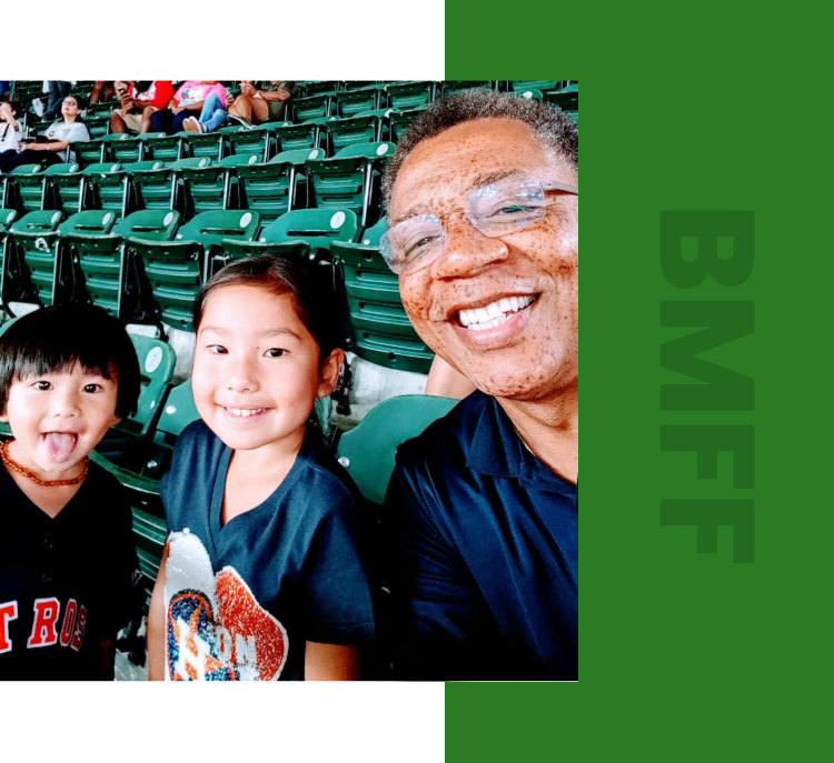 A man and two children in the stands at a baseball game.